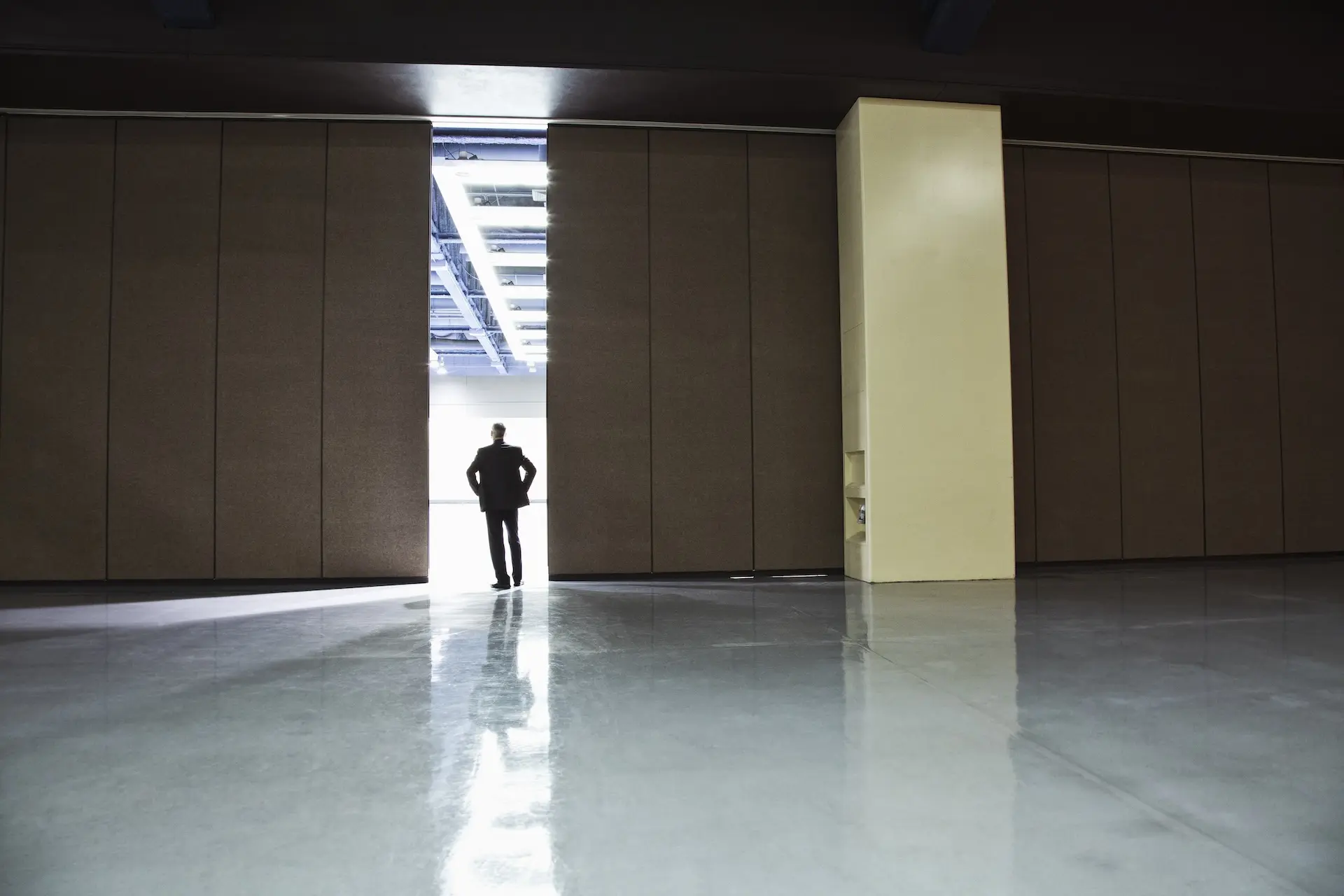 A man in a suit standing in the opening between two rooms separated by an airwall