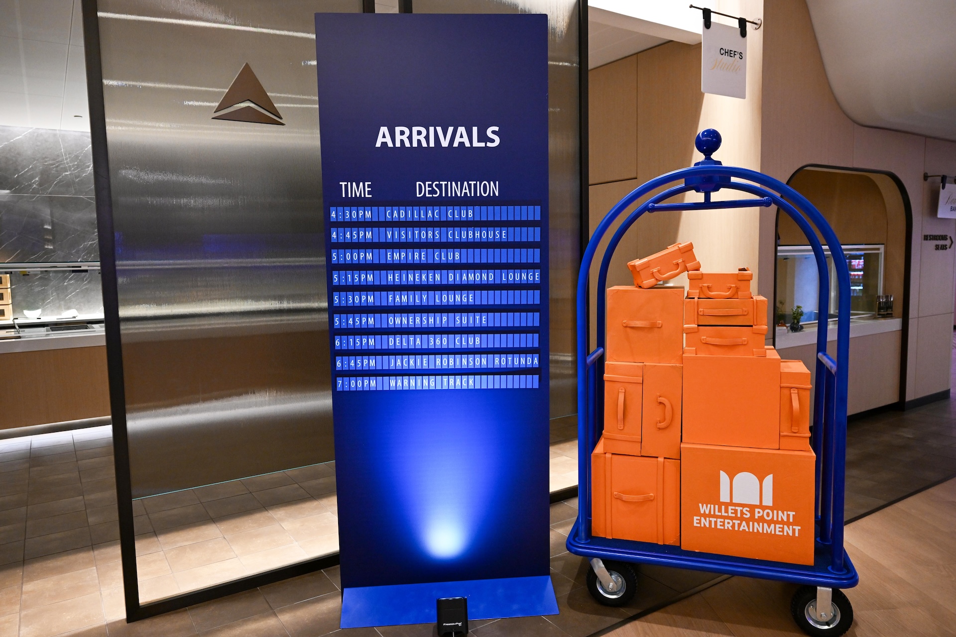 An event display featuring a stack of orange suitcases and an arrivals board with text