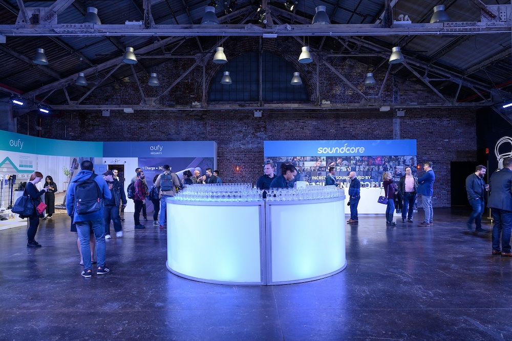 A bar in the middle of an event space with screens spanning the walls