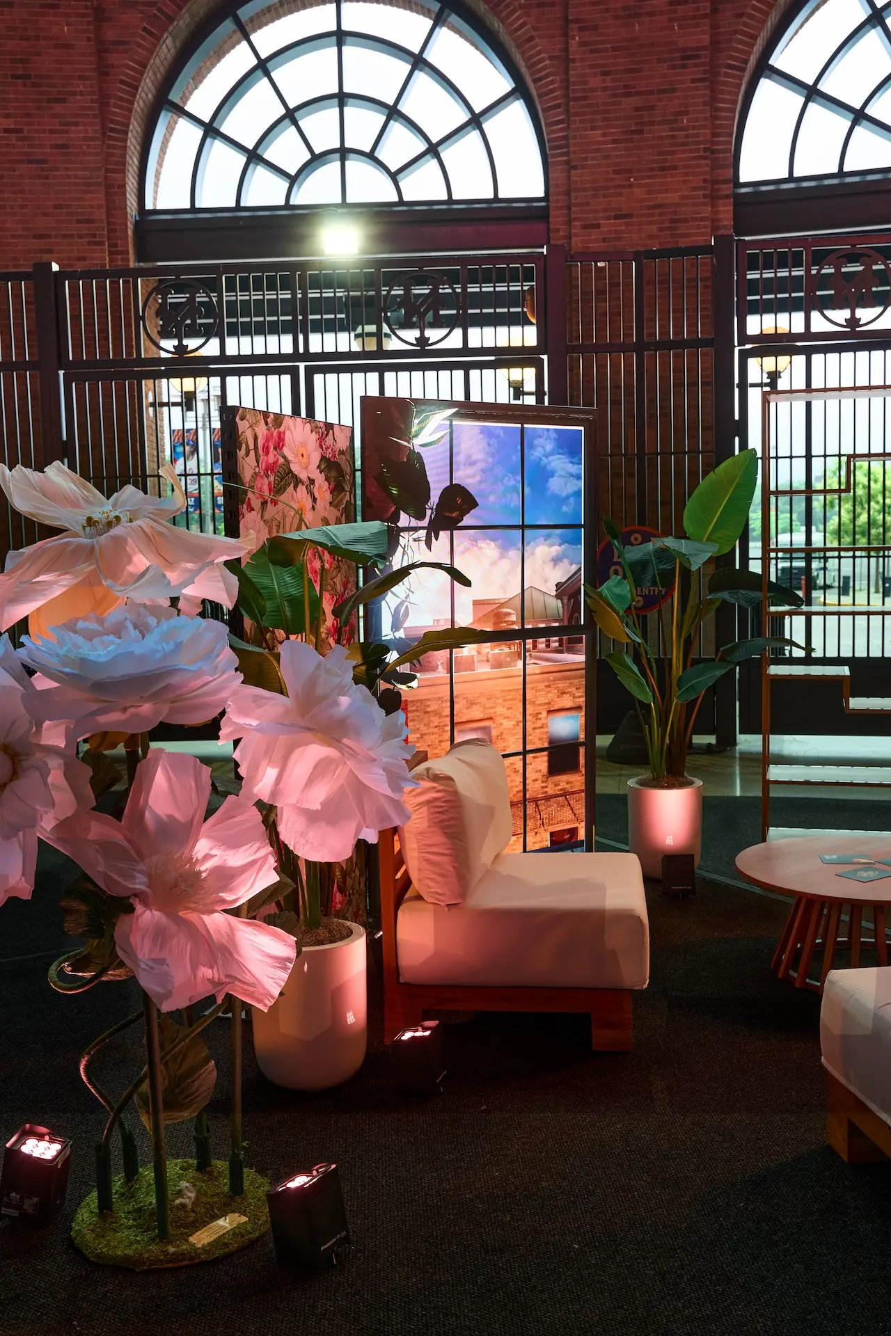 An LED totem made to resemble a window with a char and table in front of it with large floral hard-scenic 