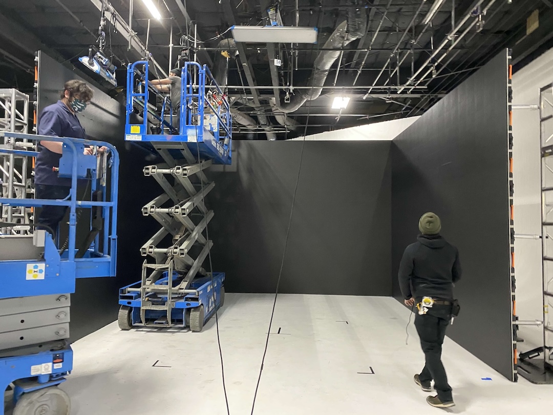 Two members of the OWEP team, one on a forklift, setting up AV equipment for a live event