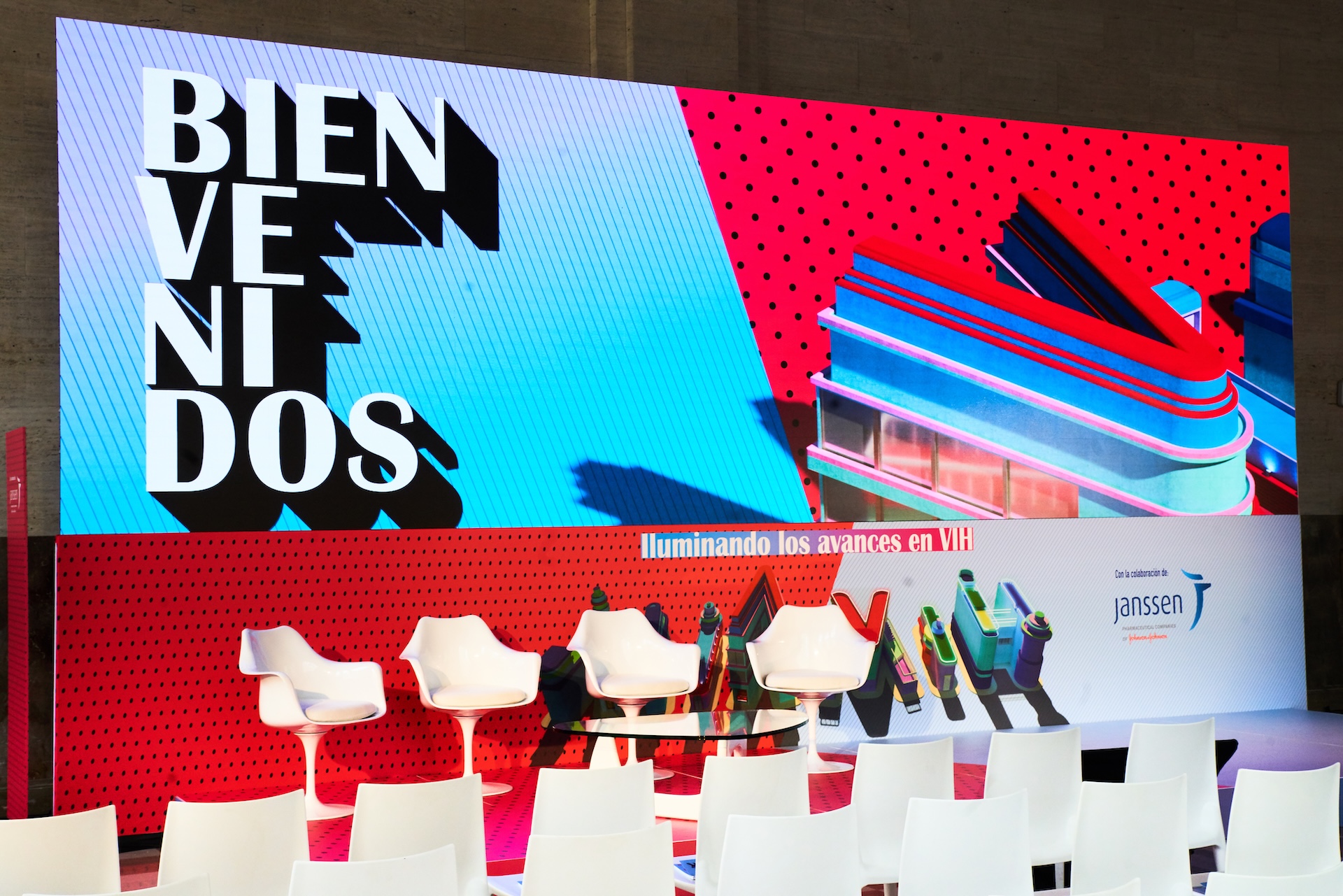 Barstools set up in front of a screen with blue and red visuals with white text