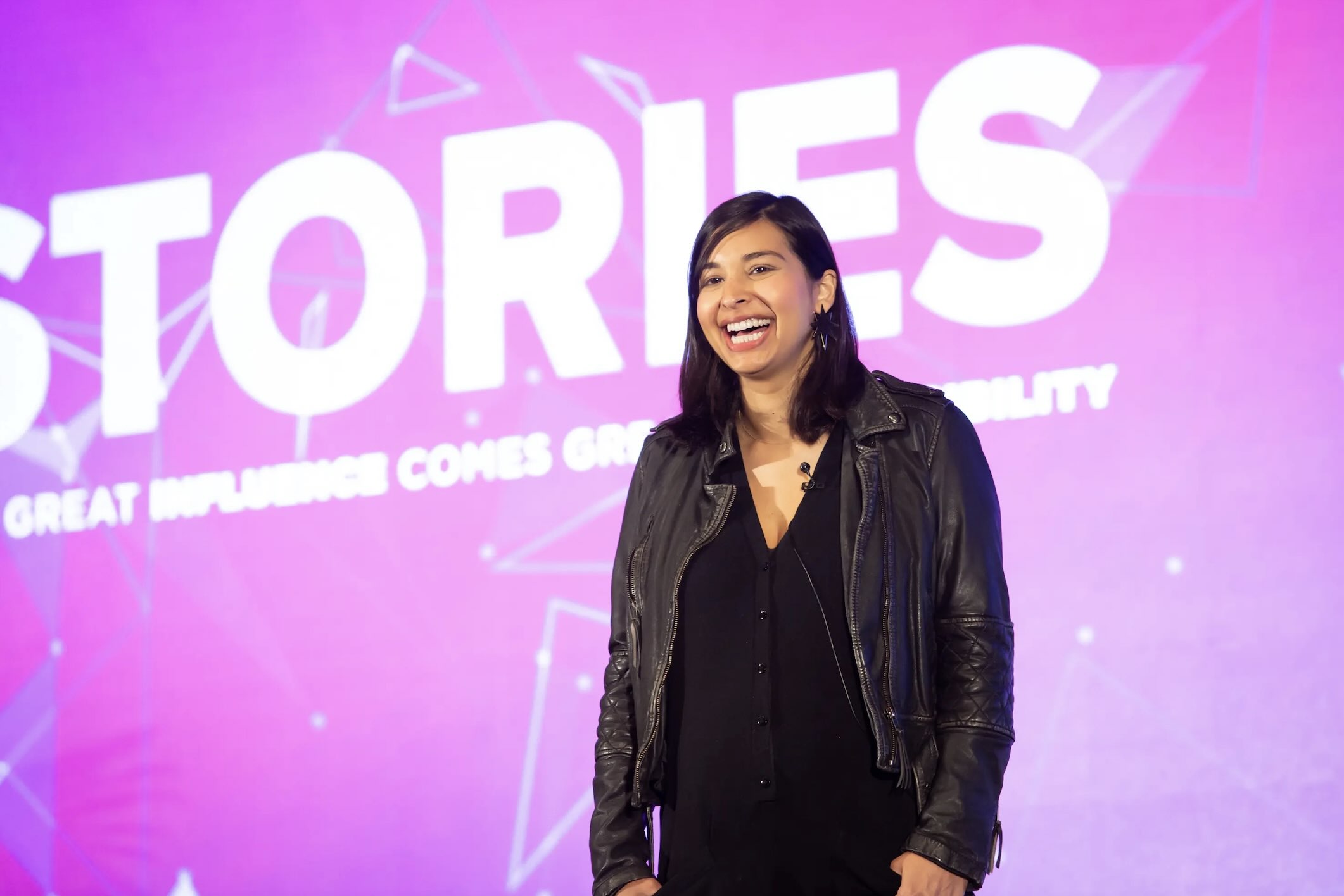 A woman presenting onstage while wearing a lav microhone